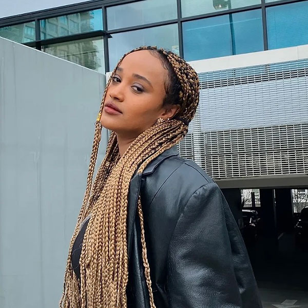 A side profile picture of Fasika Kelile. posing and Wearing a leather jacket with a more serious look