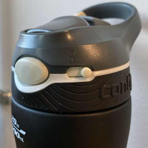 A black water bottle cap that has a control function with a button to press on and the drinking spout opens.
